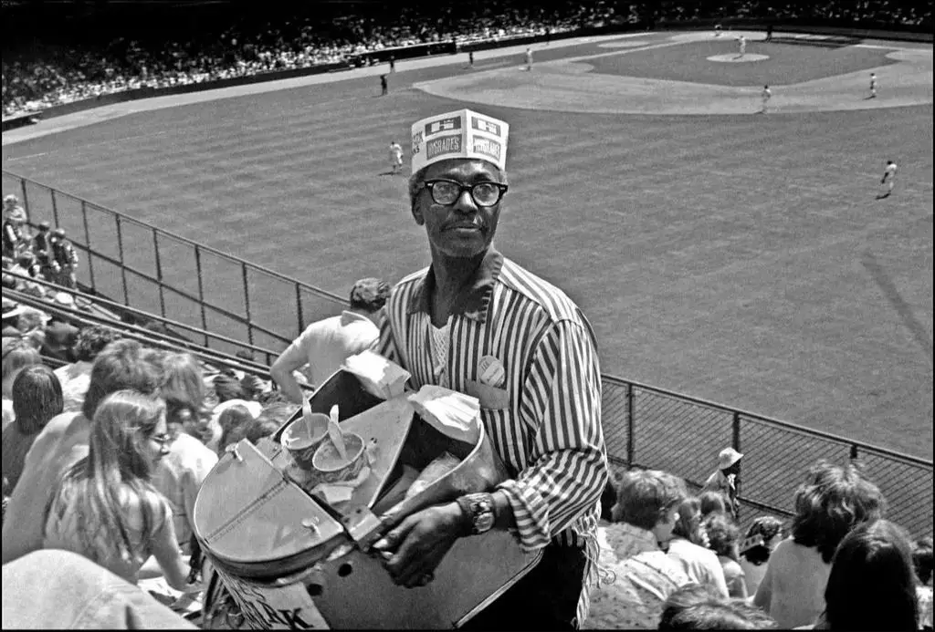 a baseball crowd enjoying hot dogs at a game in the 1920s.