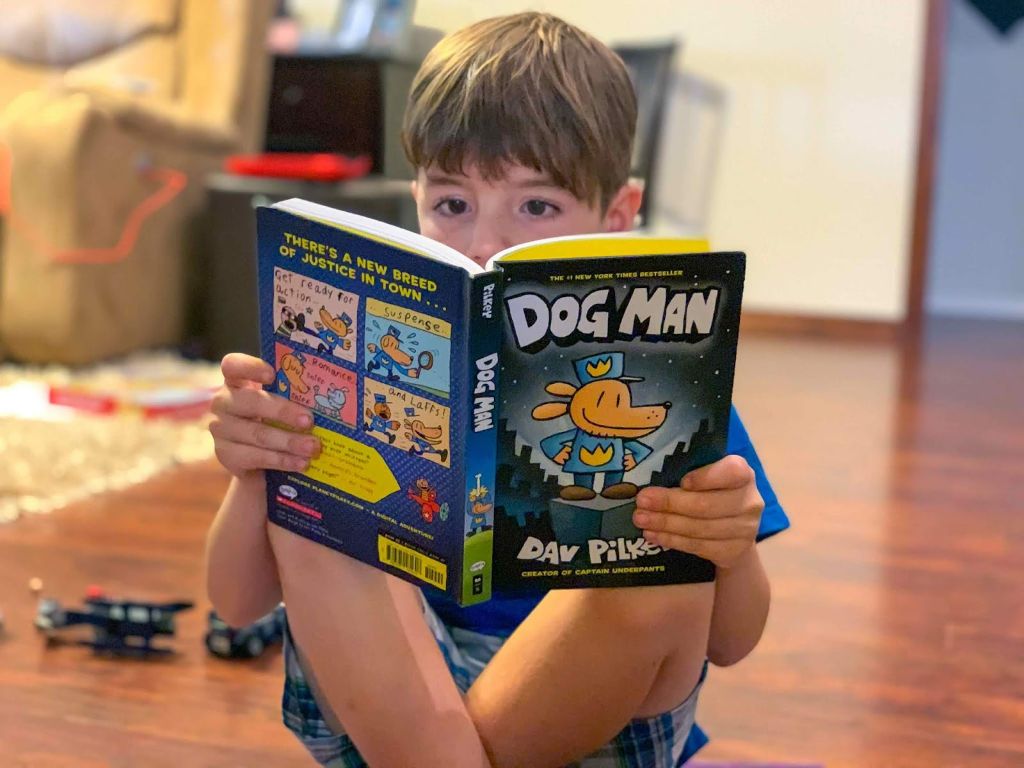 a child reading a dog man book