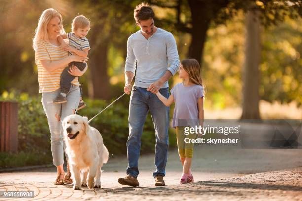 a happy family walking their dog.