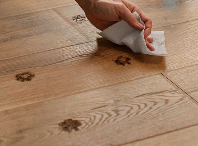 a paper towel soaking up a puddle of water on vinyl plank flooring.