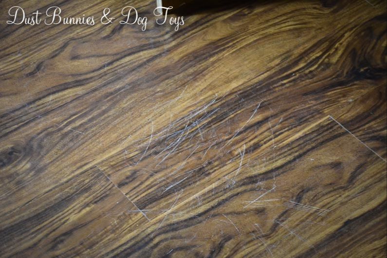 a person sanding a scratched area on luxury vinyl flooring.