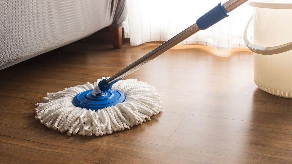 a person wiping up a puddle on lvp flooring using a mop.