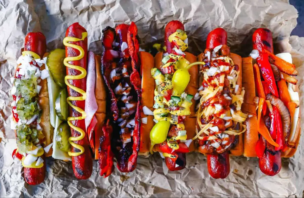 an array of global hot dog varieties with unique toppings and preparations.