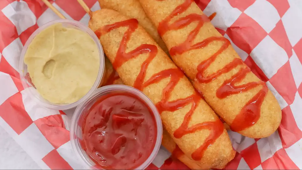 employee dipping hot dogs into cornbread batter