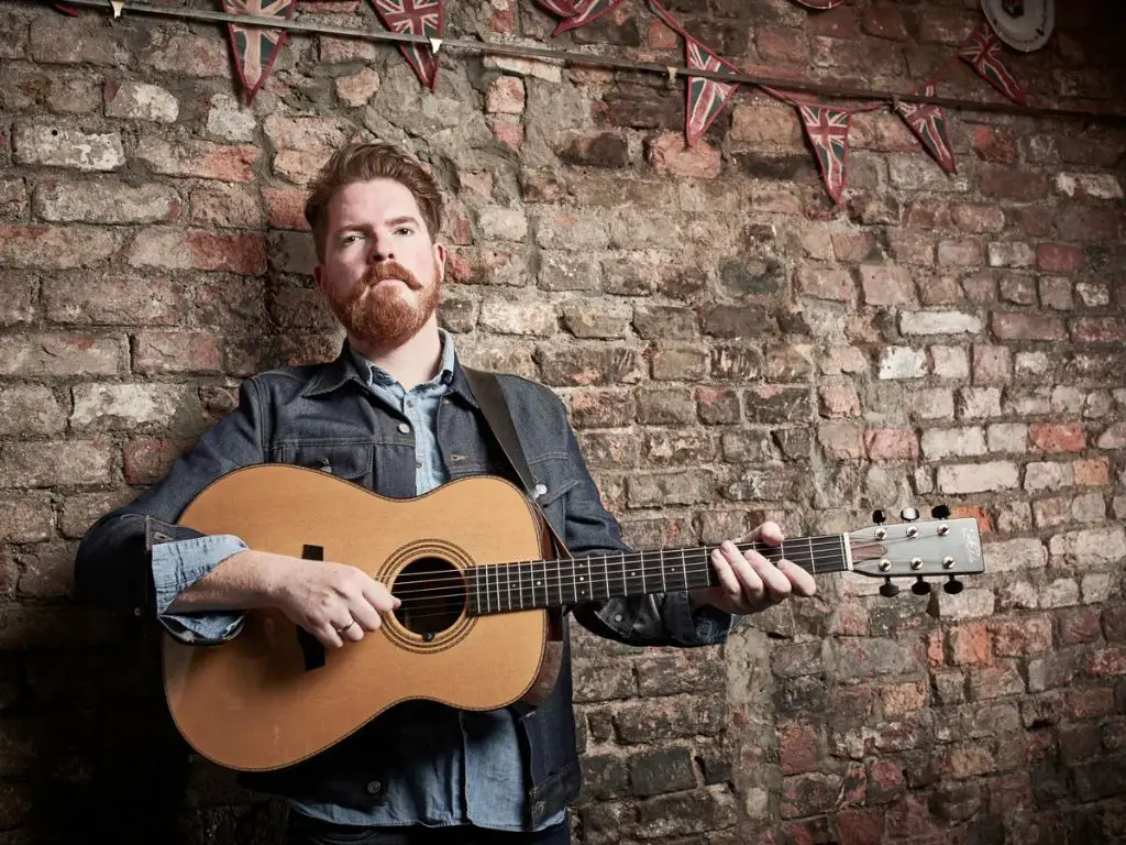 john smith singing and playing guitar at the front of the stage