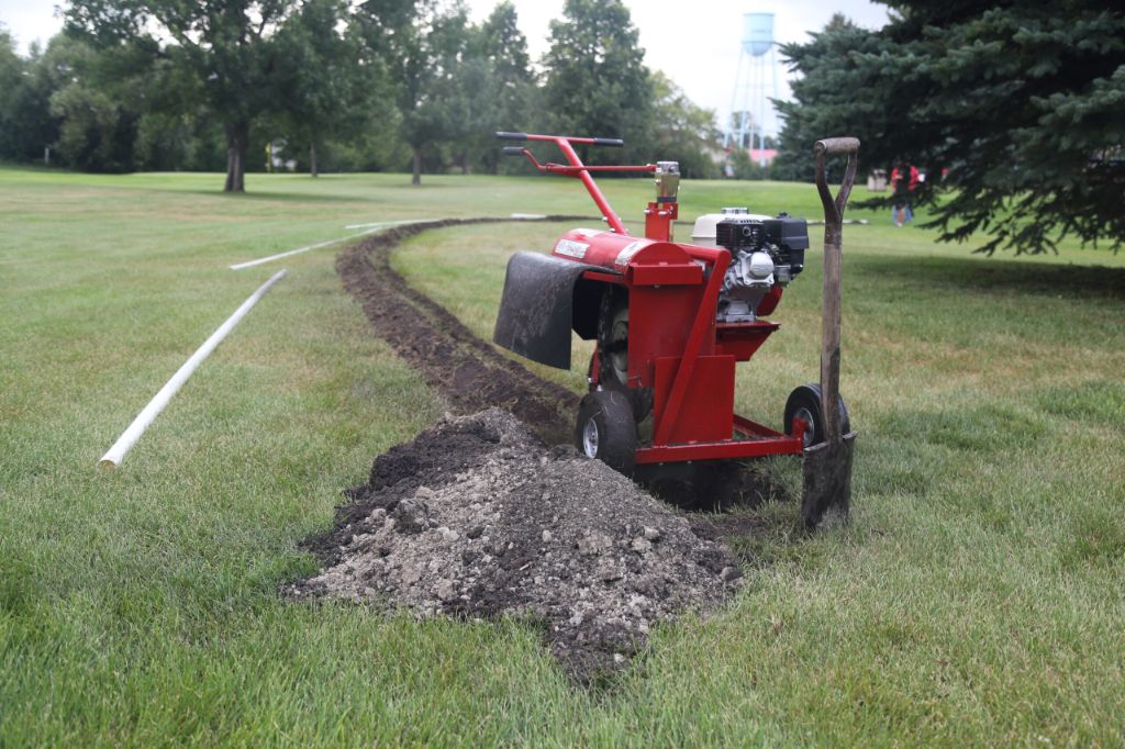 person digging trench to bury electric dog fence wire