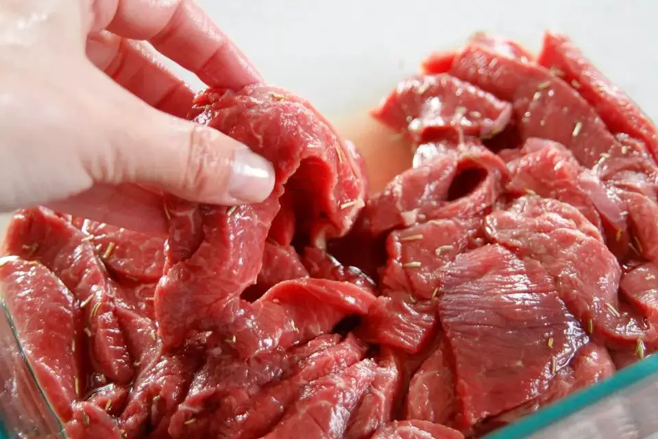 raw dog meat being sliced to make jerky