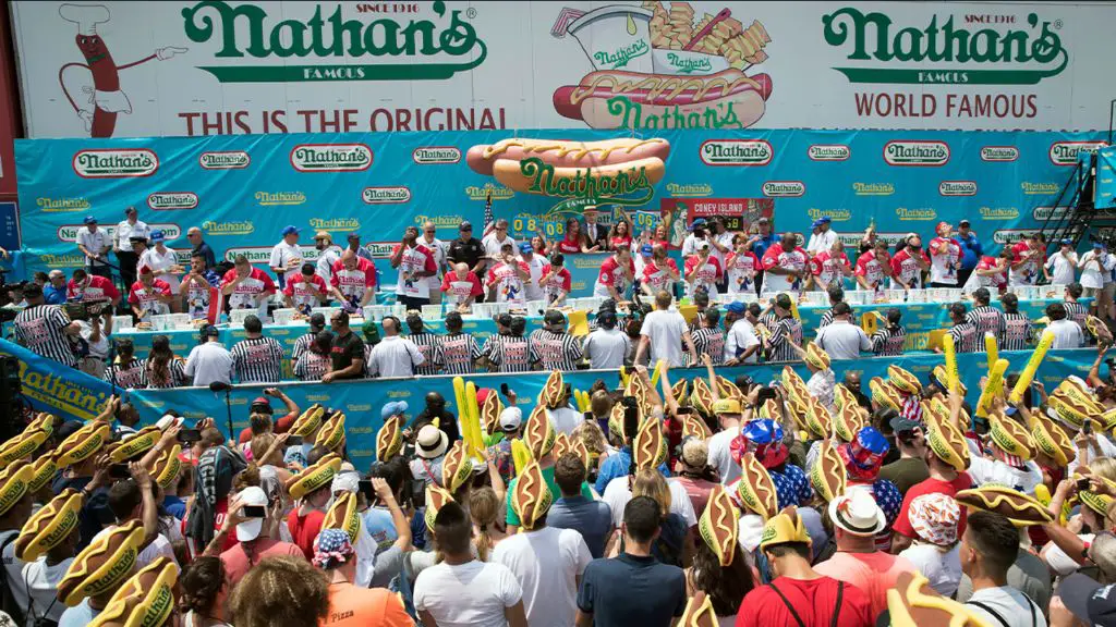 the crowd at the nathan's hot dog eating contest cheering on the competitive eaters.